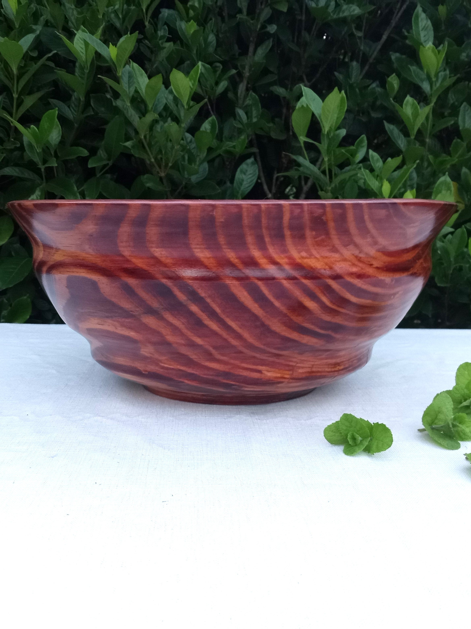 a huge red oak wood burl bowl with swirls of cream, red, black and burnt sienna tones spiraling around an "eye of the storm" pattern in the sidewall