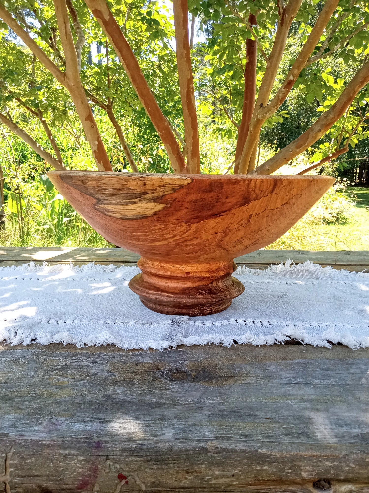 a huge red oak wood burl bowl with swirls of cream, red, black and burnt sienna tones spiraling around an "eye of the storm" pattern in the sidewall