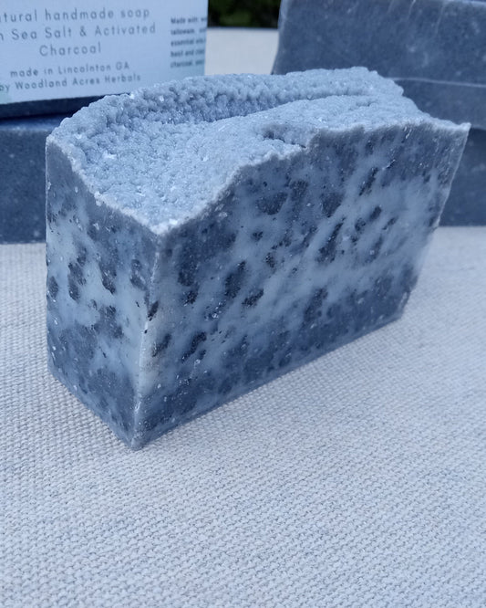 a black and white speckled bar of soap that looks like granite with sharp edges and a rustic sculpted top set on white fabric 