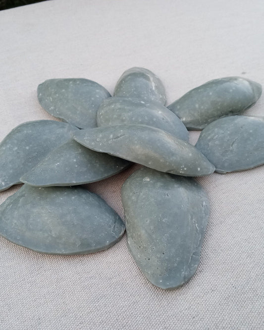 gray clam shell shaped soaps in a pile on a beige linen cloth